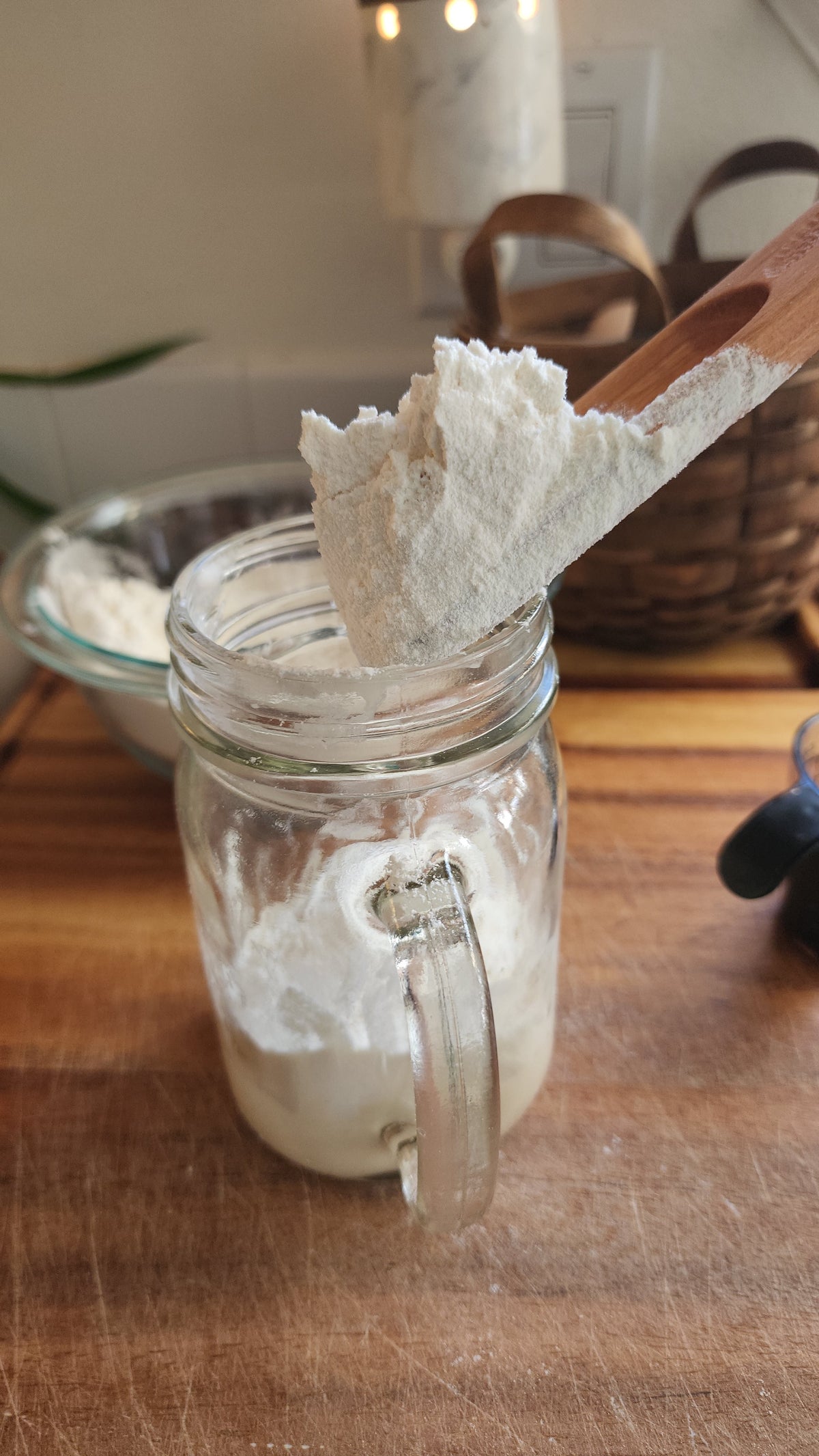 The Spatula holding flour above a starter jar