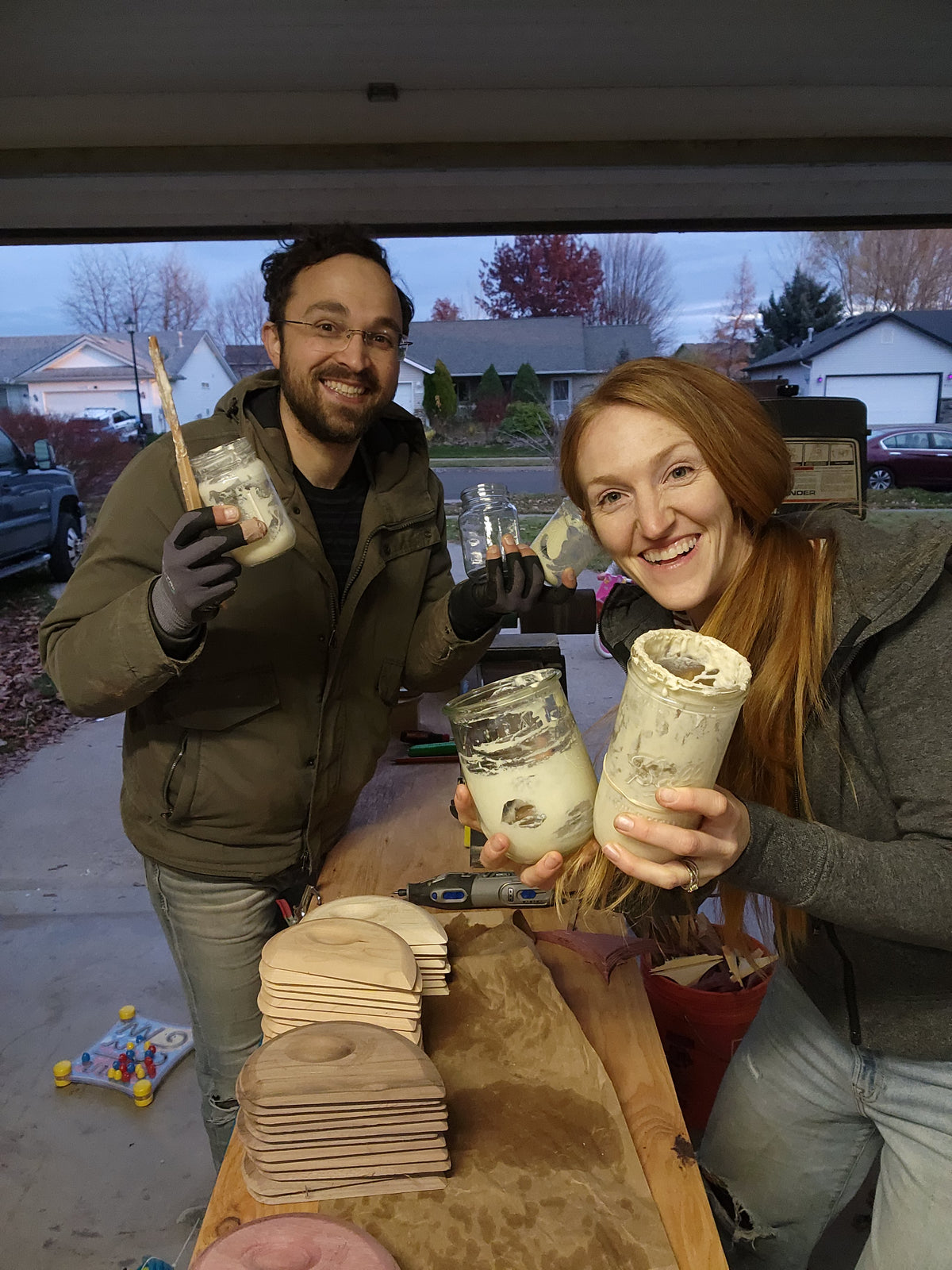 Josh and Kirtley holding starter jars beside a bench of unfinished tools