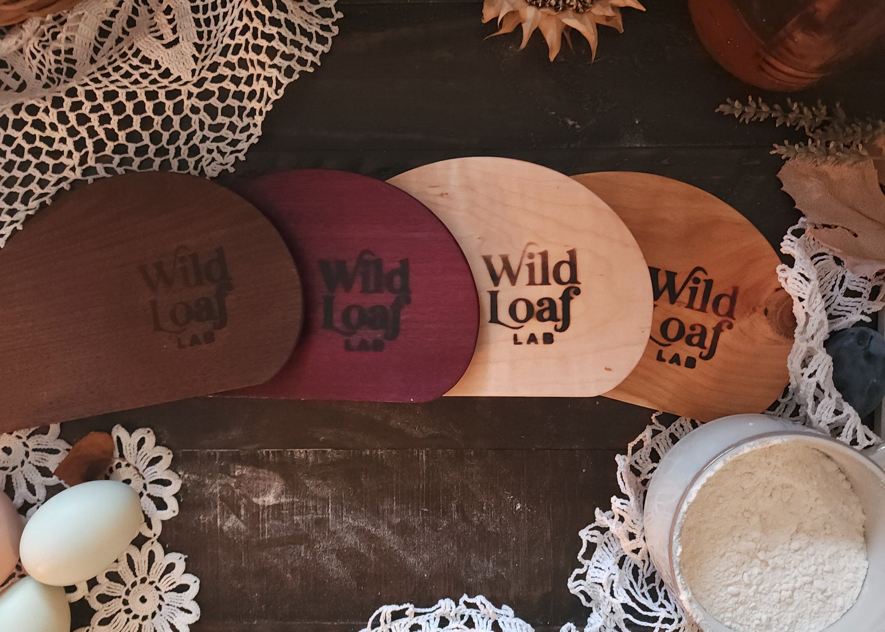 Wooden loafers with 'Wild Loaf' branding on a rustic surface with lace and natural elements.